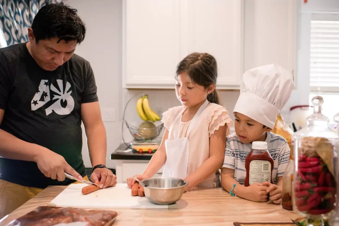 Father and two young children cooking together in a bright kitchen capturing the joy of cooking with kids at home.