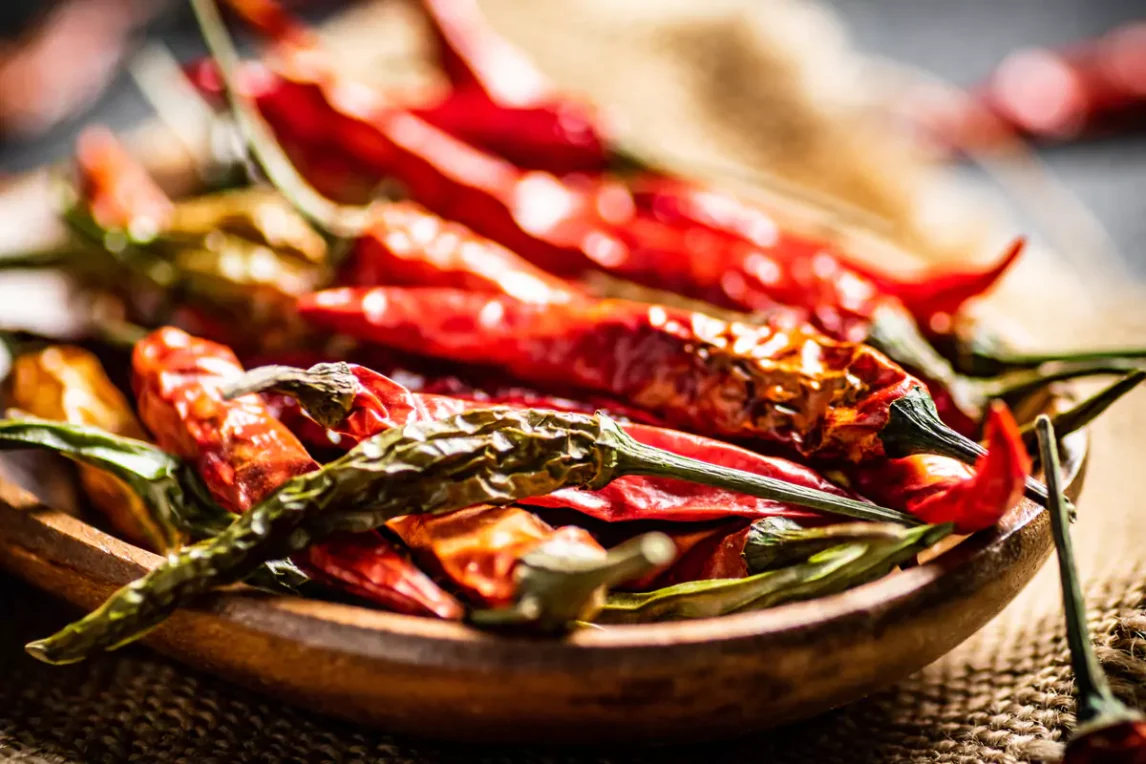 Close-up of assorted dried chiles in a wooden bowl showcasing texture and variety.